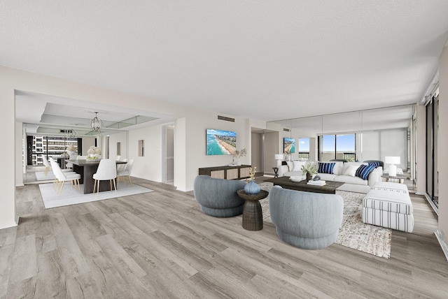 living area with visible vents, a raised ceiling, and wood finished floors