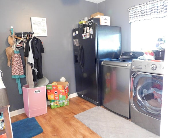 clothes washing area featuring wood finished floors, laundry area, baseboards, and separate washer and dryer