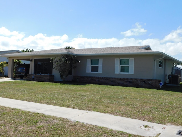 ranch-style home featuring brick siding, central air condition unit, a front lawn, a carport, and stucco siding