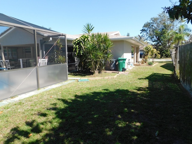 view of yard featuring glass enclosure and fence