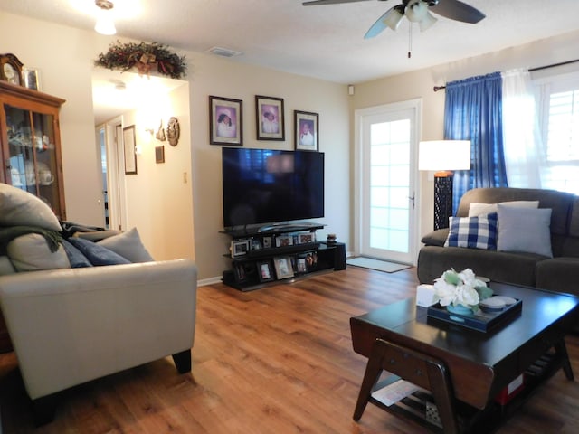 living room with ceiling fan, wood finished floors, and visible vents