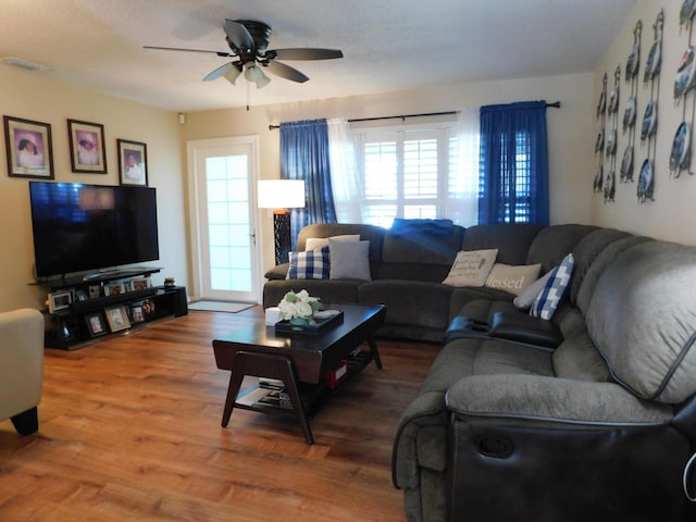 living room with a ceiling fan, visible vents, and wood finished floors