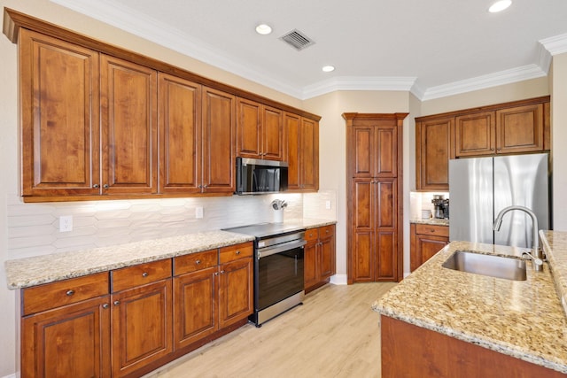 kitchen featuring light stone counters, a sink, appliances with stainless steel finishes, backsplash, and brown cabinetry