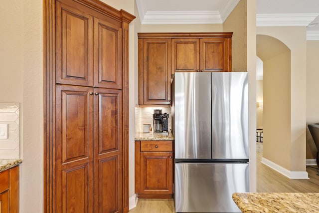 kitchen featuring ornamental molding, freestanding refrigerator, light wood-style flooring, and light stone countertops