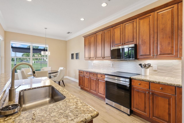 kitchen featuring light stone counters, electric stove, decorative light fixtures, and a sink