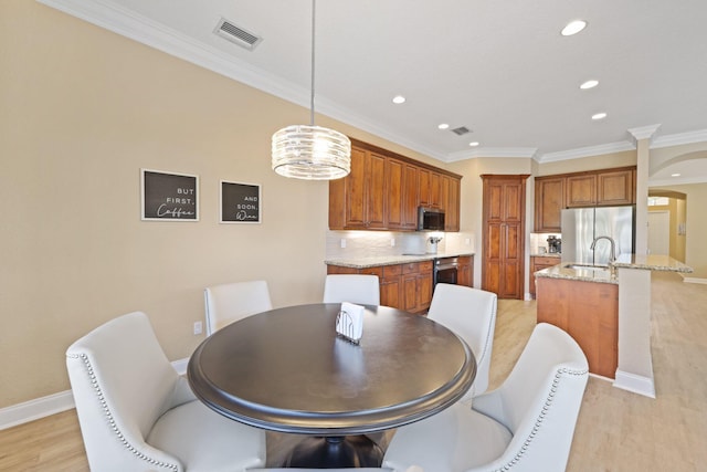 dining room with light wood finished floors, baseboards, visible vents, crown molding, and recessed lighting