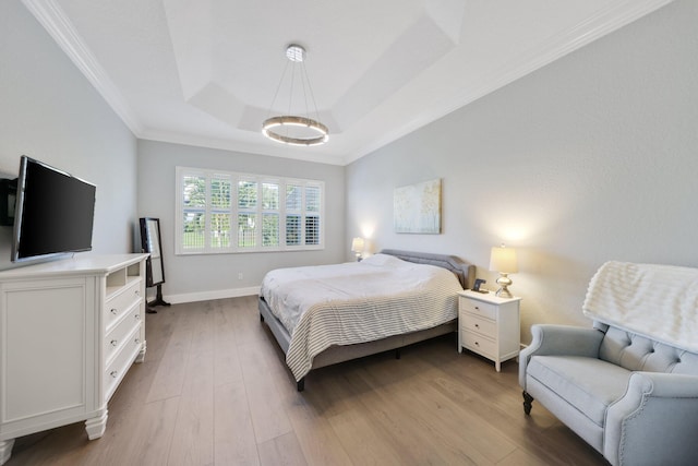 bedroom with ornamental molding, wood finished floors, a raised ceiling, and baseboards