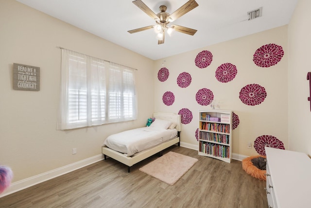 bedroom featuring a ceiling fan, wood finished floors, visible vents, and baseboards