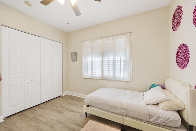 bedroom with light wood finished floors, ceiling fan, baseboards, and a closet