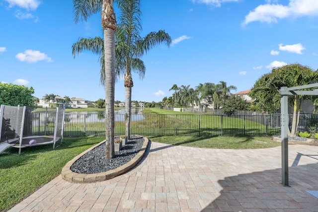 view of patio / terrace featuring a water view, a fenced backyard, and a trampoline