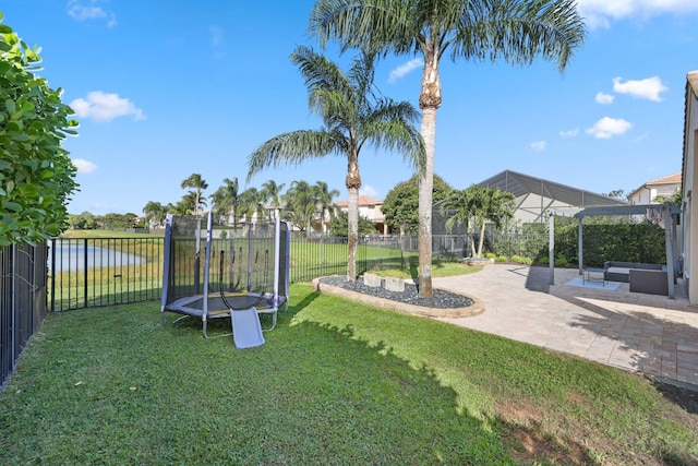 view of playground featuring a yard, a trampoline, a water view, and a fenced backyard