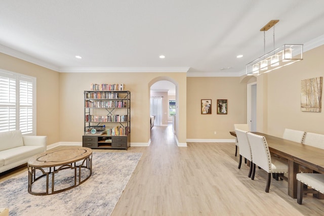 living area featuring light wood-style flooring, arched walkways, baseboards, and ornamental molding