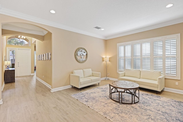 living room with arched walkways, light wood-style flooring, visible vents, and crown molding