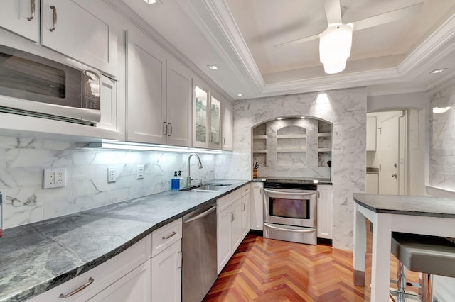 kitchen with stainless steel appliances, white cabinetry, glass insert cabinets, and a sink