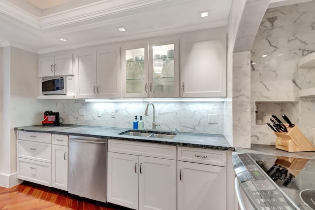 kitchen with stainless steel appliances, a sink, white cabinets, glass insert cabinets, and crown molding