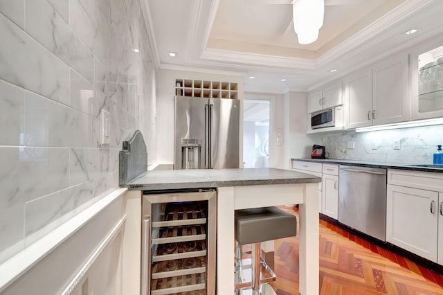 kitchen with white cabinetry, wine cooler, appliances with stainless steel finishes, and a raised ceiling