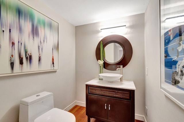 bathroom with toilet, baseboards, wood finished floors, and vanity