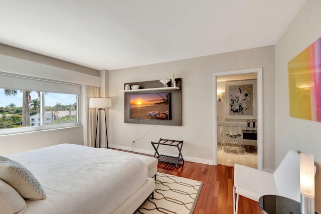 bedroom featuring baseboards, wood finished floors, and ensuite bathroom