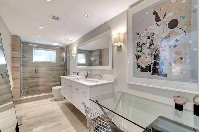 bathroom featuring double vanity, visible vents, toilet, a stall shower, and a sink