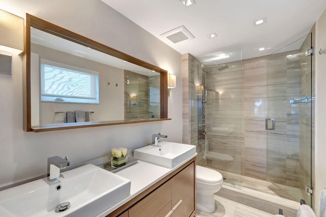 bathroom with a stall shower, visible vents, a sink, and toilet