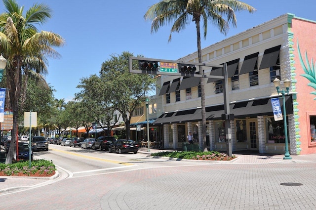 view of road featuring sidewalks, traffic lights, street lights, and curbs