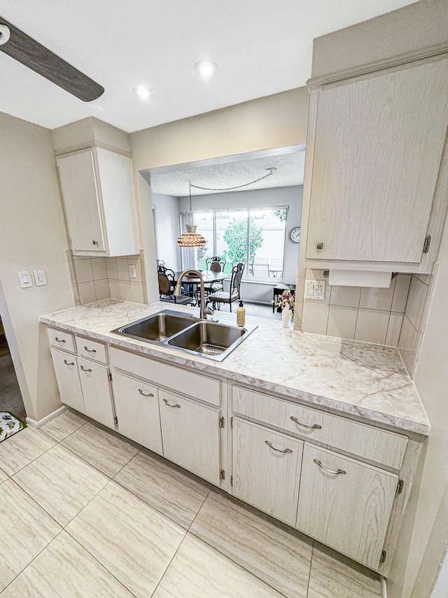 kitchen featuring light countertops, backsplash, a sink, and decorative light fixtures