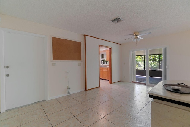 unfurnished room with a textured ceiling, light tile patterned floors, visible vents, and a ceiling fan