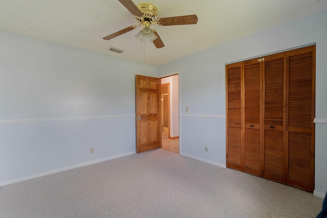 unfurnished bedroom featuring baseboards, visible vents, a closet, and light colored carpet