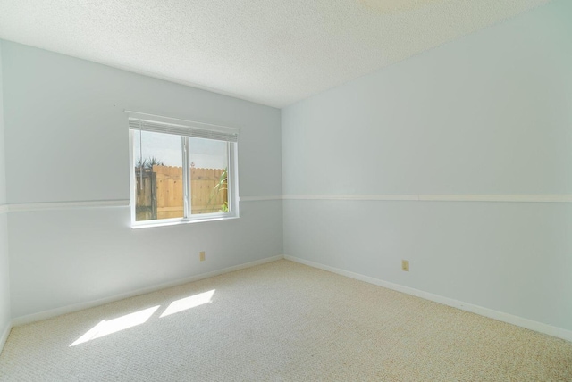 carpeted spare room featuring baseboards and a textured ceiling