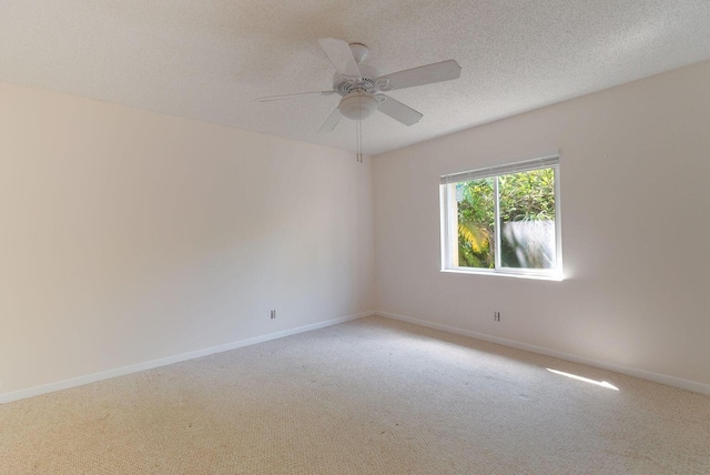 spare room featuring a ceiling fan, light colored carpet, a textured ceiling, and baseboards