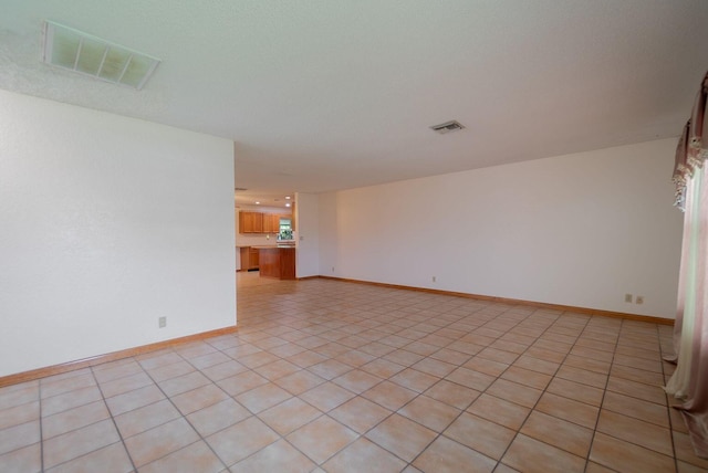 empty room featuring light tile patterned floors, baseboards, and visible vents