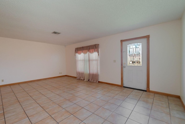 entrance foyer featuring a textured ceiling, light tile patterned flooring, visible vents, and baseboards