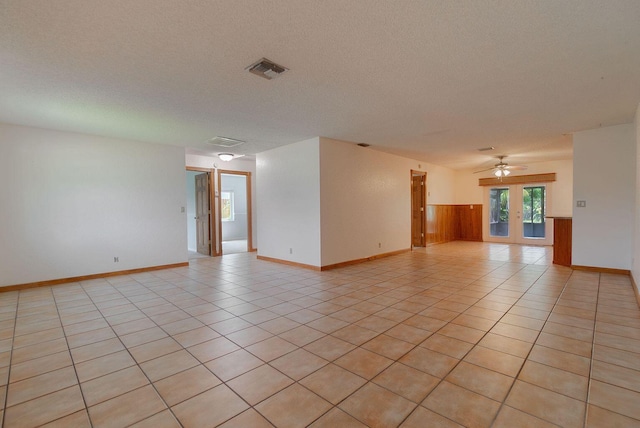 spare room with light tile patterned floors, french doors, and a textured ceiling