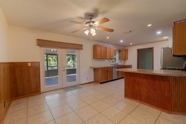 kitchen featuring a peninsula, light countertops, appliances with stainless steel finishes, french doors, and brown cabinets