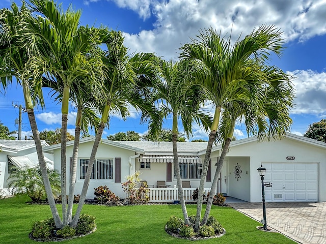 single story home featuring a garage, a front yard, decorative driveway, and stucco siding