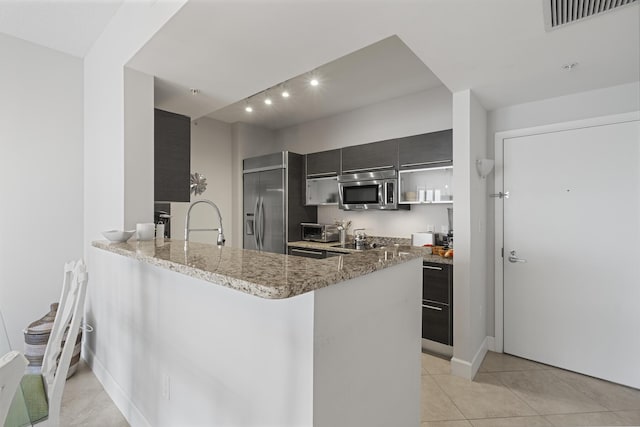 kitchen with stainless steel appliances, visible vents, a sink, light stone countertops, and a peninsula