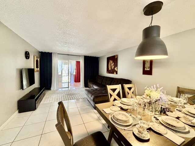 dining space with baseboards, a textured ceiling, and light tile patterned flooring