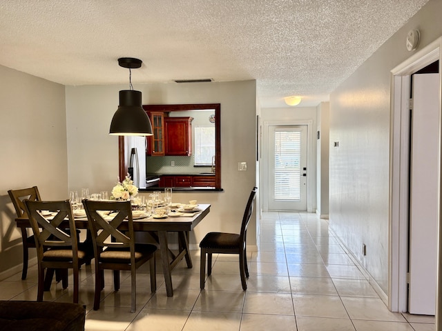 dining area featuring visible vents, a textured ceiling, baseboards, and light tile patterned floors