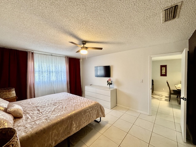 bedroom with light tile patterned floors, ceiling fan, a textured ceiling, visible vents, and baseboards