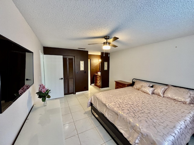 bedroom featuring a ceiling fan, a textured ceiling, and light tile patterned floors