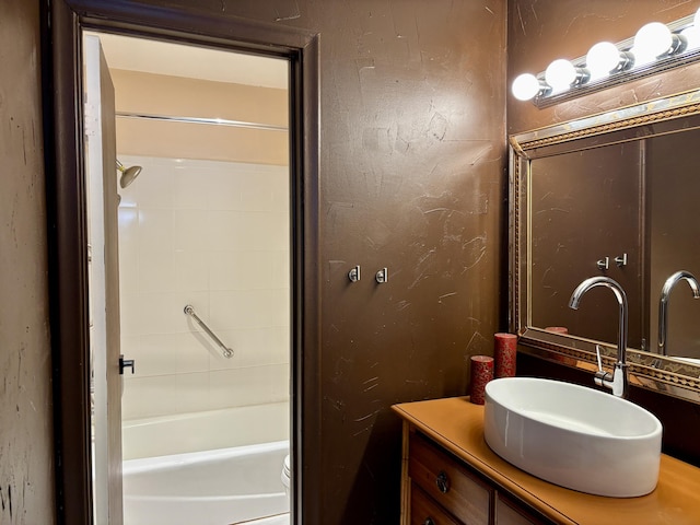 full bath with a textured wall, shower / tub combination, and vanity