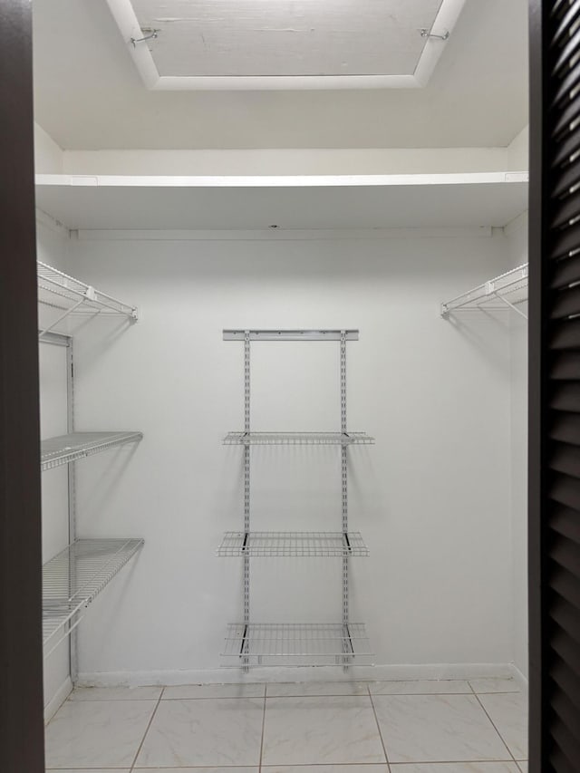 walk in closet featuring marble finish floor