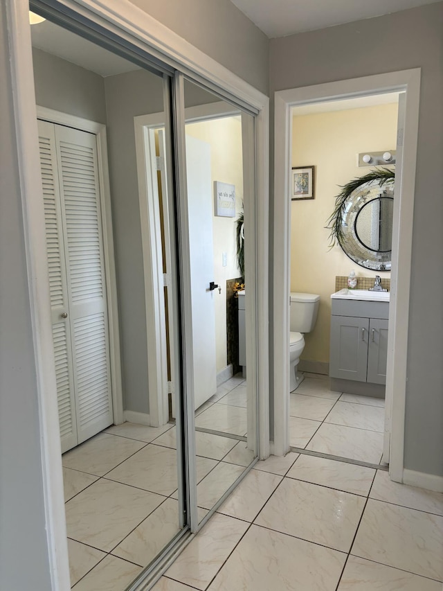 corridor featuring baseboards and a sink