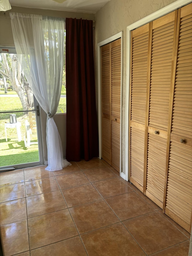 corridor with a textured wall and dark tile patterned flooring