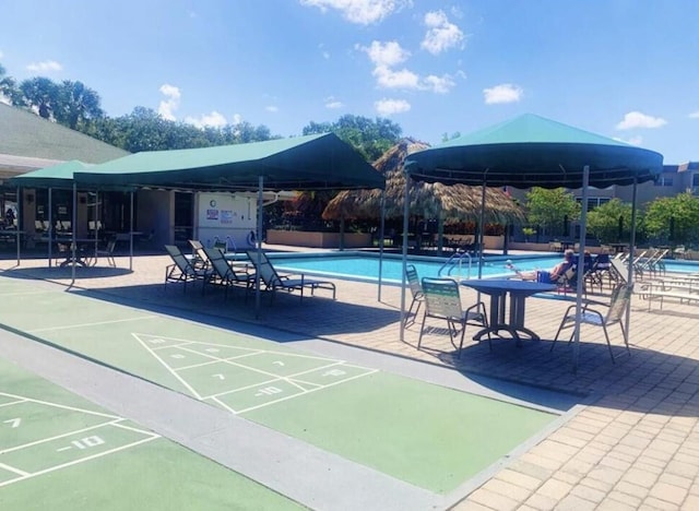 view of property's community featuring shuffleboard, a swimming pool, and fence