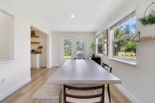 dining room with light wood-style flooring, baseboards, and french doors