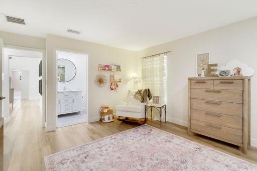 living area with light wood-style flooring, visible vents, and baseboards