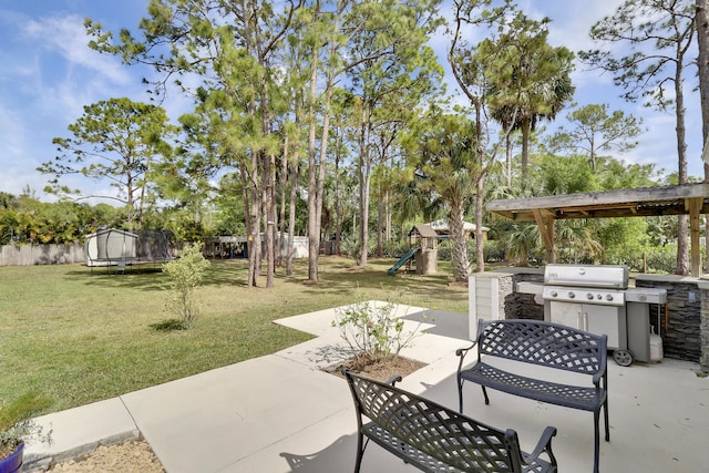 view of patio / terrace with a trampoline, fence, a playground, and area for grilling