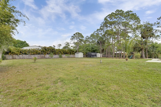 view of yard with a storage shed, fence, and an outbuilding