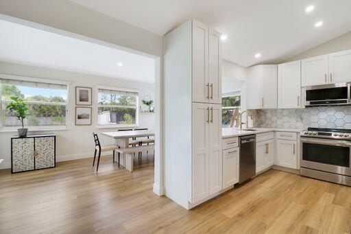 kitchen featuring tasteful backsplash, light wood-style flooring, appliances with stainless steel finishes, light countertops, and white cabinetry